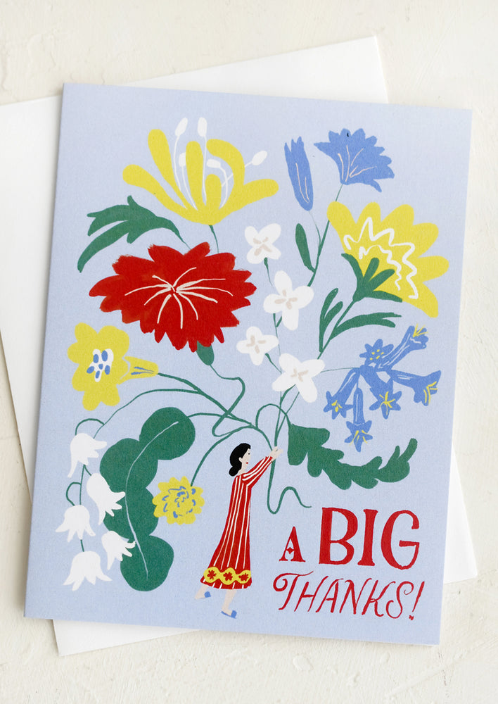 A greeting card with illustration of tiny woman holding giant flowers.