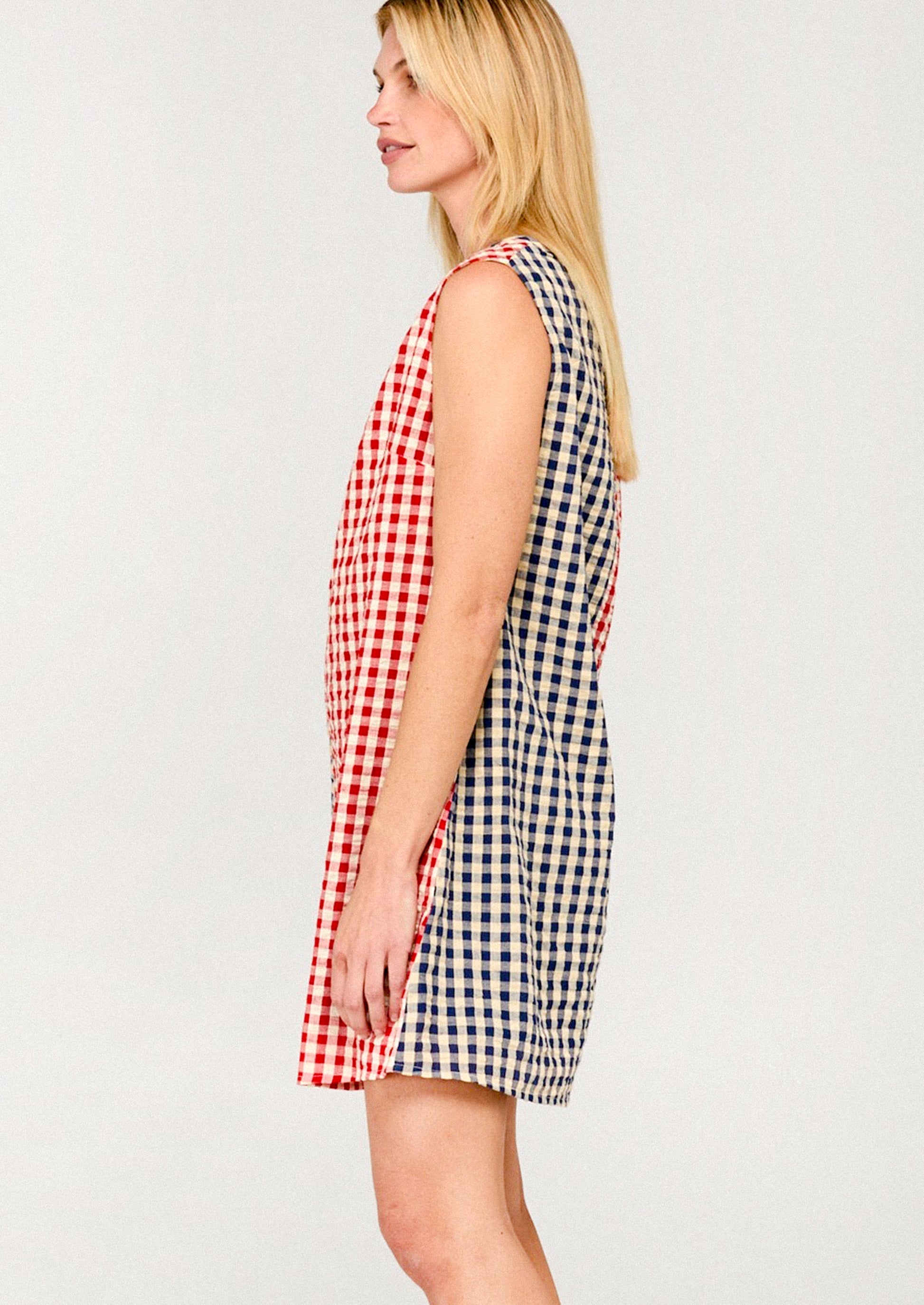 Woman wearing a red, white, and blue checkered dress on a light gray background