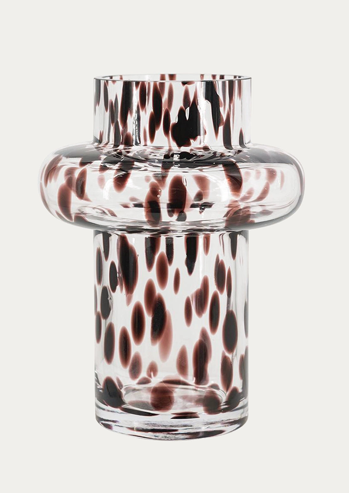A clear glass vase with a rounded middle section and a flared top, decorated with a pattern of dark brown and reddish-brown spots.
