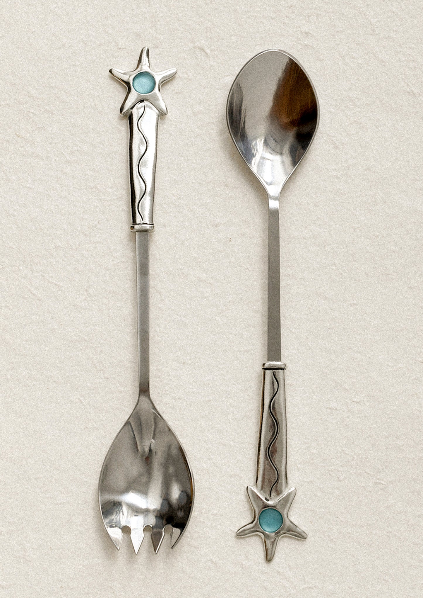 Two decorative spoons with star and turquoise stone designs on a light background