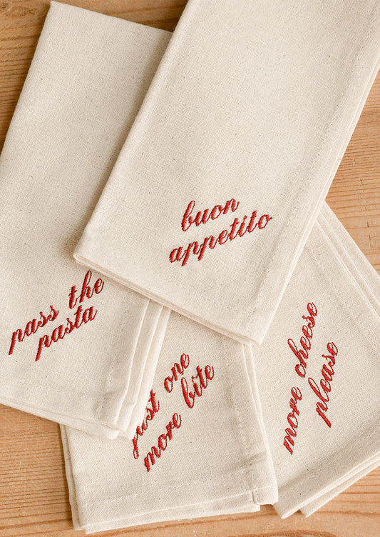 Four cream-colored cotton napkins with red embroidered Italian phrases.