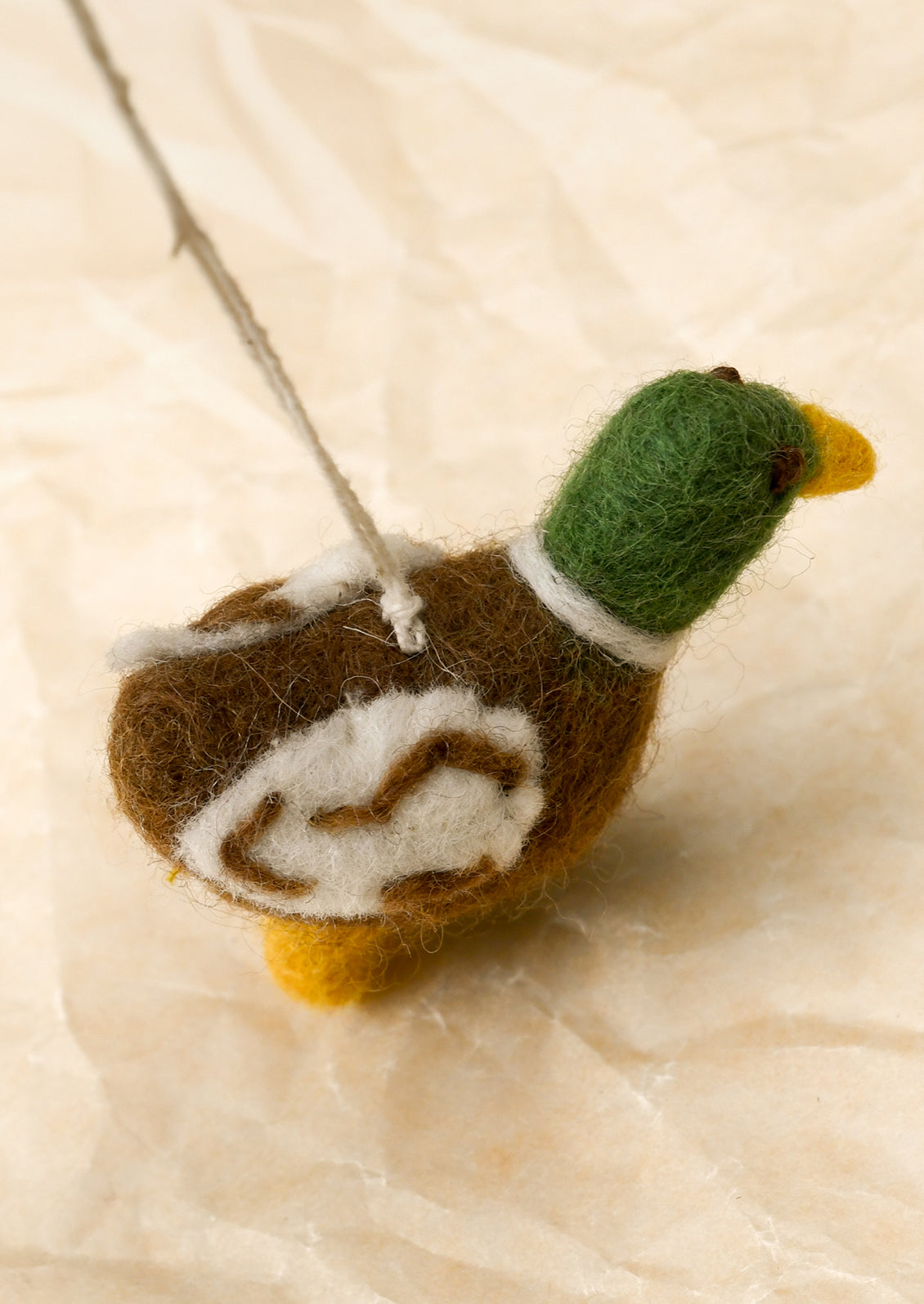 A small felted wool ornament depicting a mallard duck.