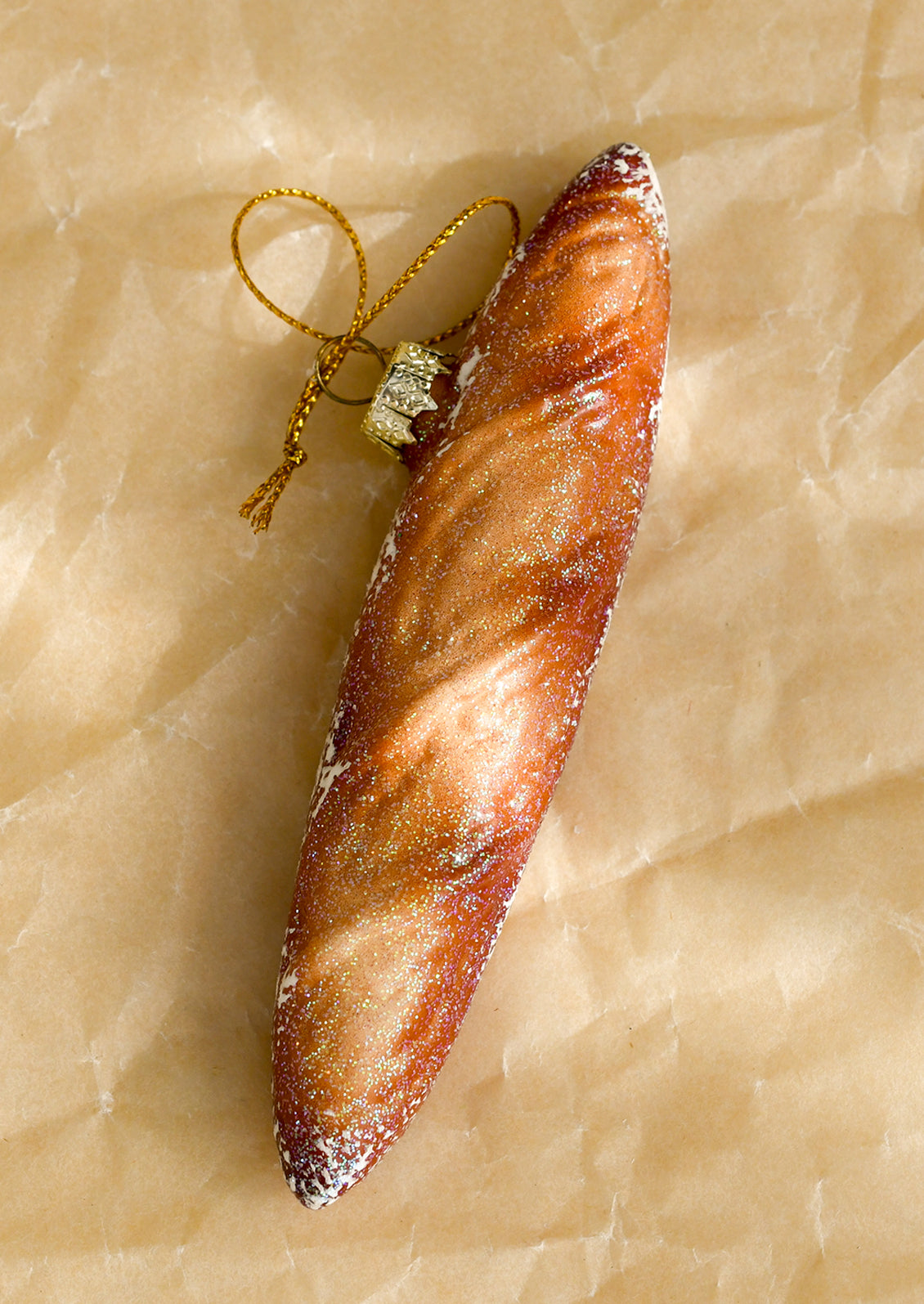 A glass ornament depicting a pointy-end baguette with glitter details.
