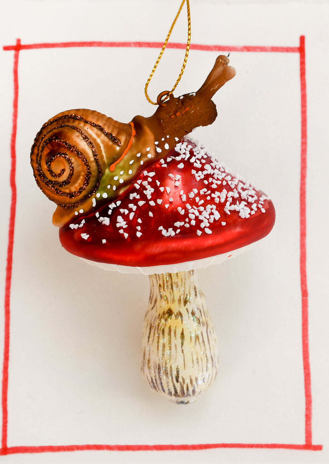 A glass ornament depicting a snail on a red mushroom.