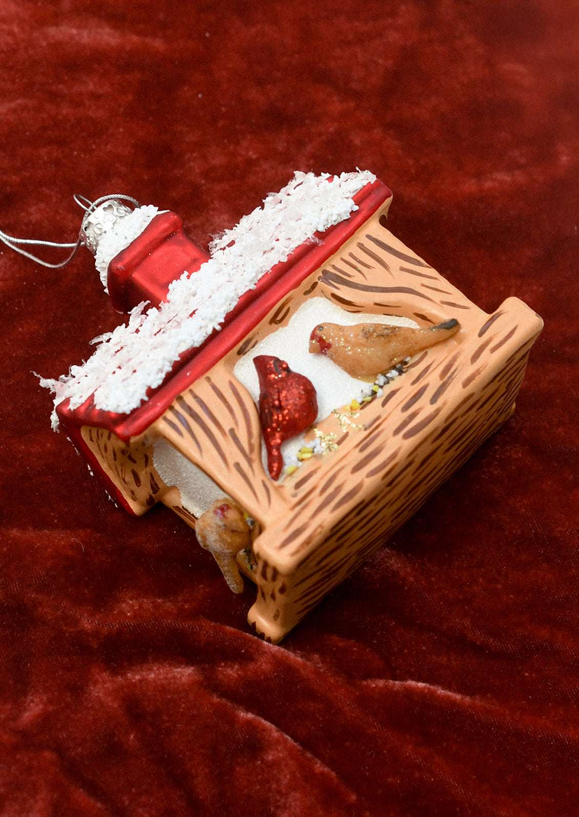 A glass ornament depicting a bird feeder with cardinal and other bird.
