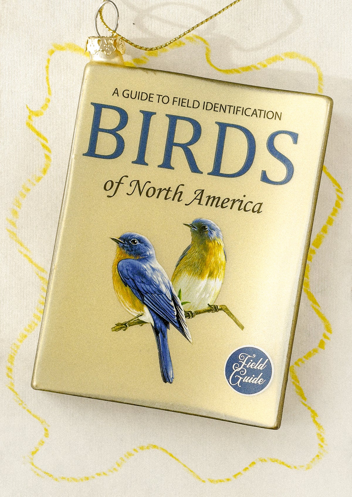 A glass ornament depicting a bird field guide book.