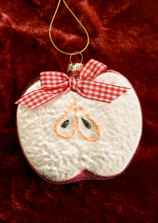 A glass ornament depicting a half apple, decorated with a red gingham bow.
