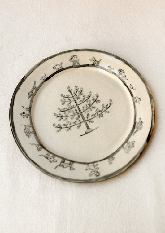 A cream plate with animal and tree drawing in dark grey.