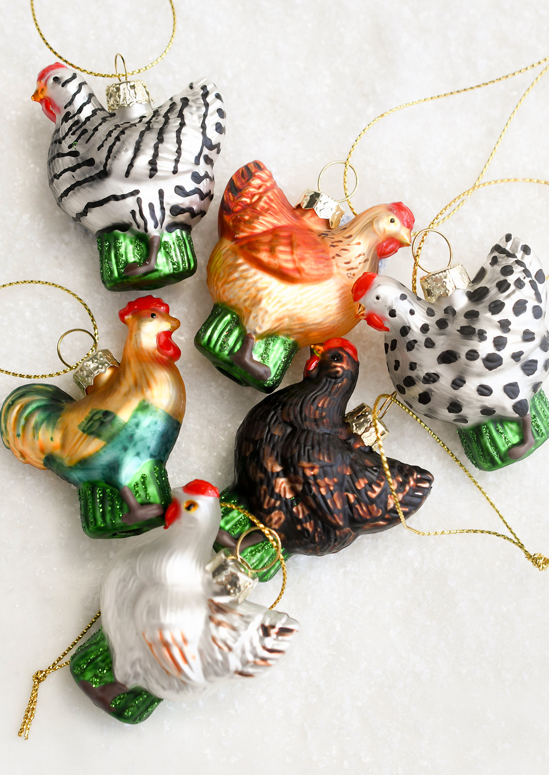 Small glass ornaments depicting chickens in assorted colors.