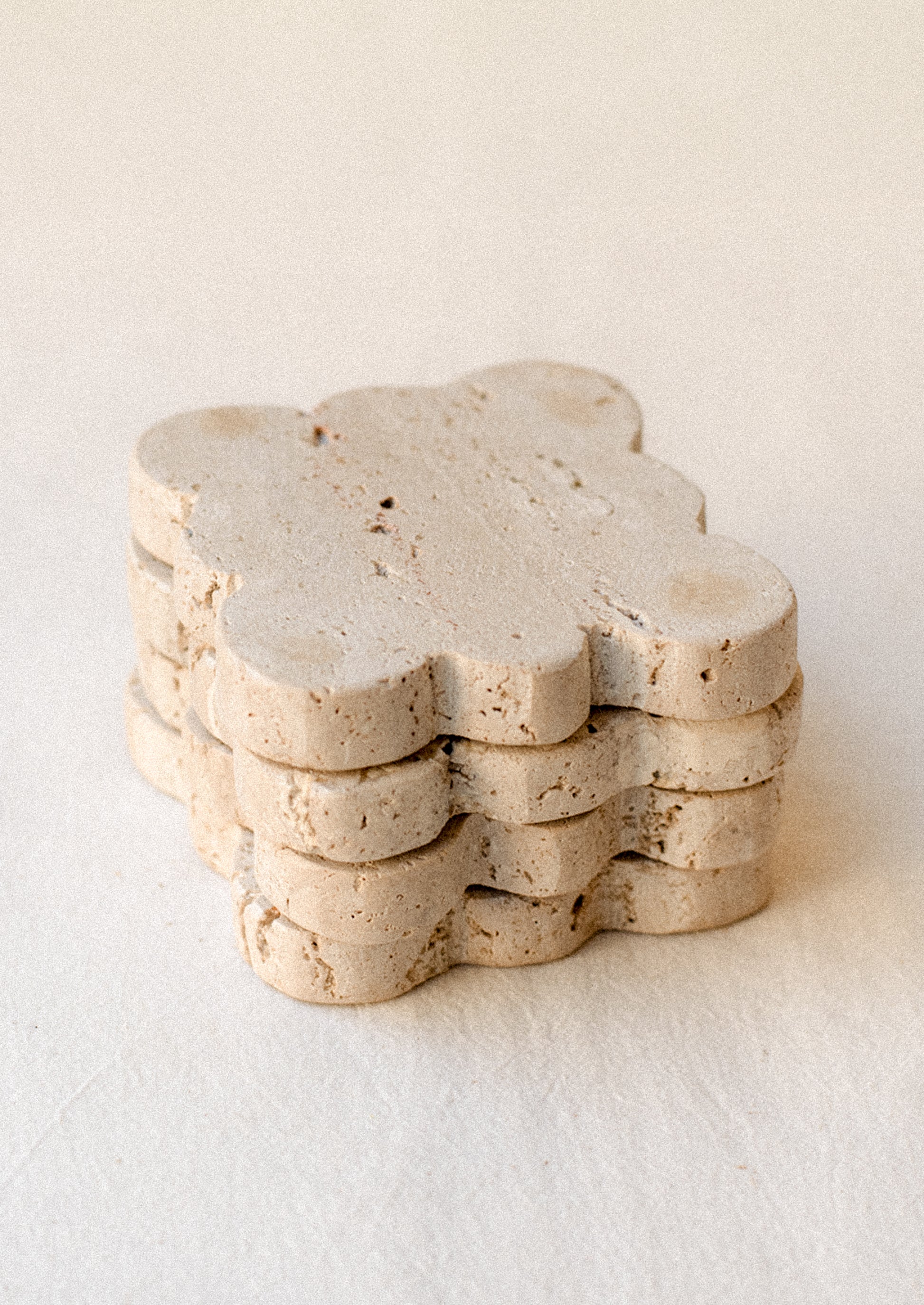 A set of square travertine coasters with scalloped edges.