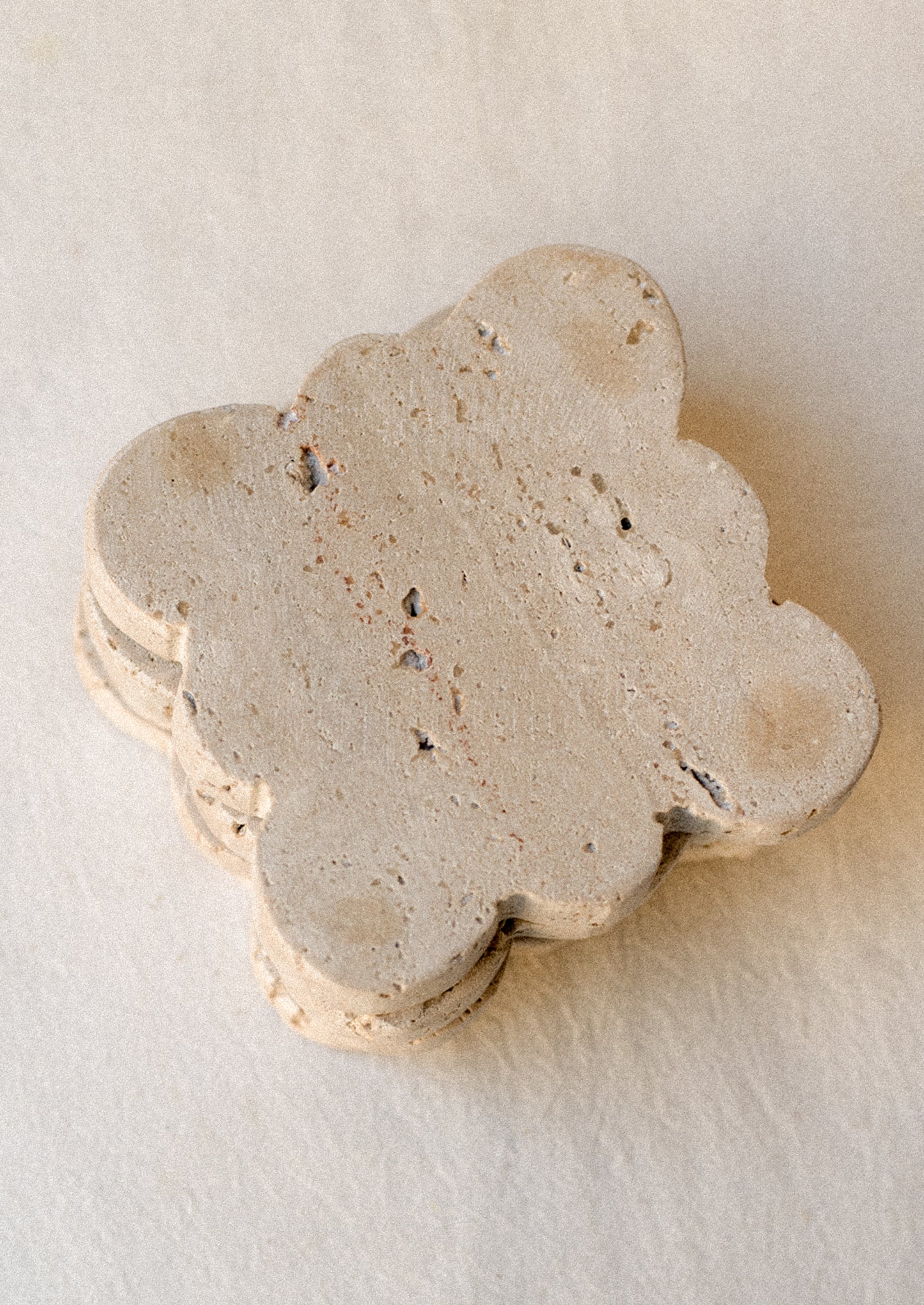 A set of square travertine coasters with scalloped edges.