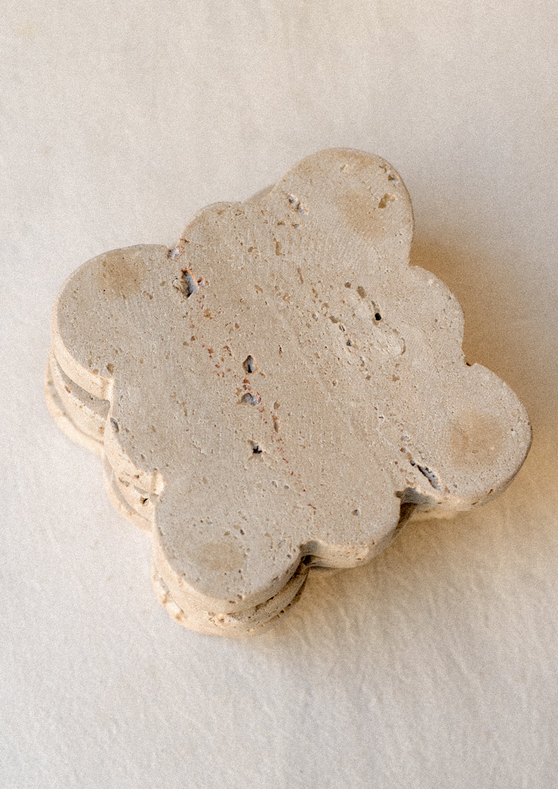 A set of square travertine coasters with scalloped edges.
