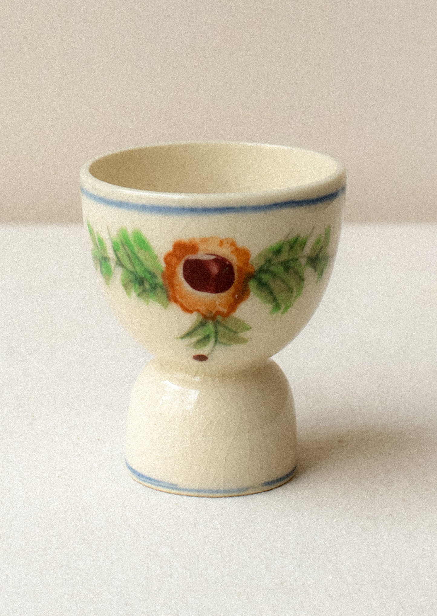 A floral egg cup with blue stripe border and floral design.
