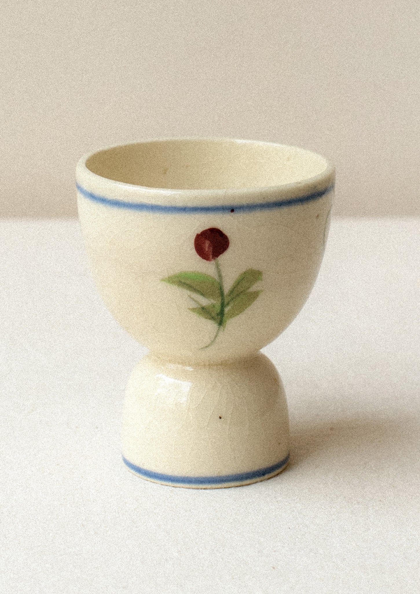 A floral egg cup with blue stripe border and floral design.