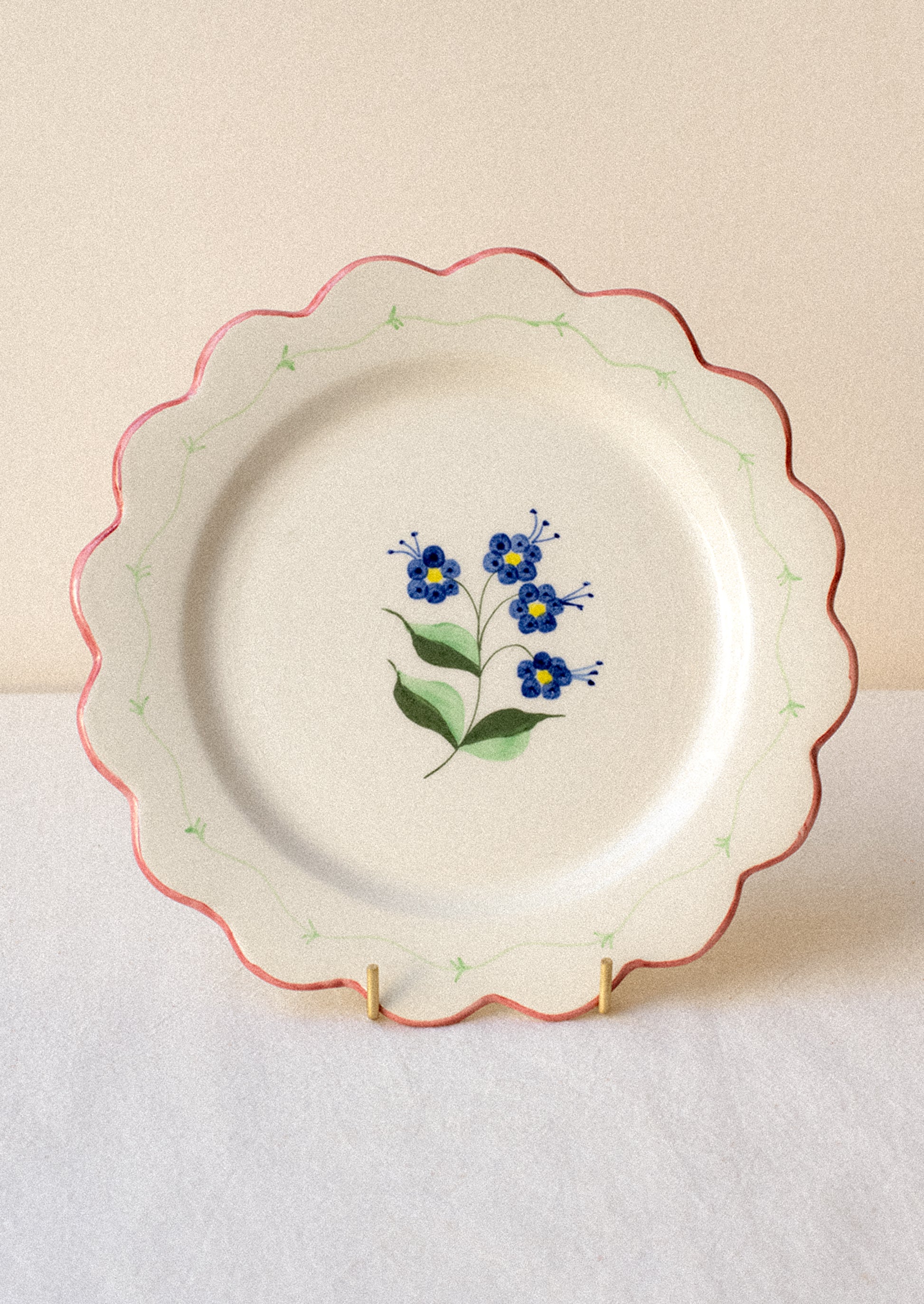 Decorative ceramic plate with blue floral design and pink scalloped edge.