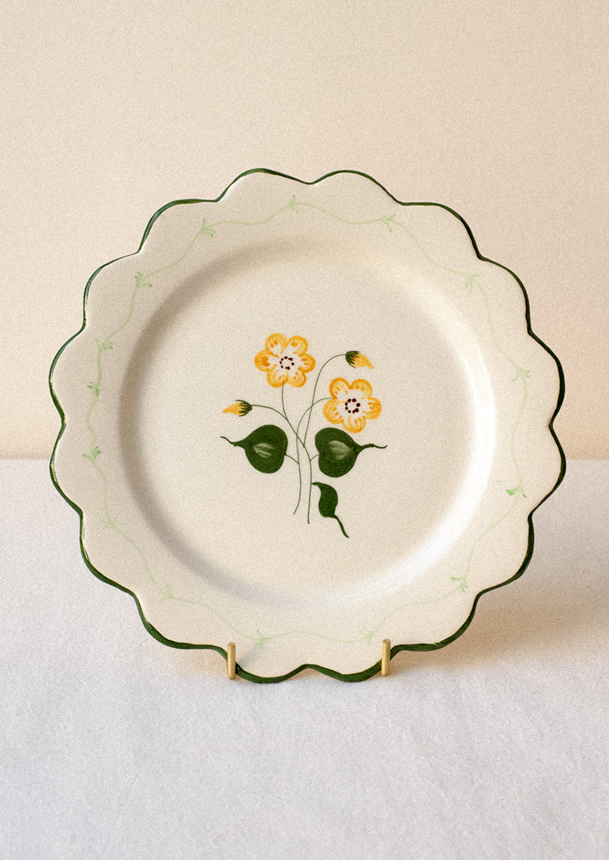 Decorative ceramic plate with yellow floral design and green scalloped edge.