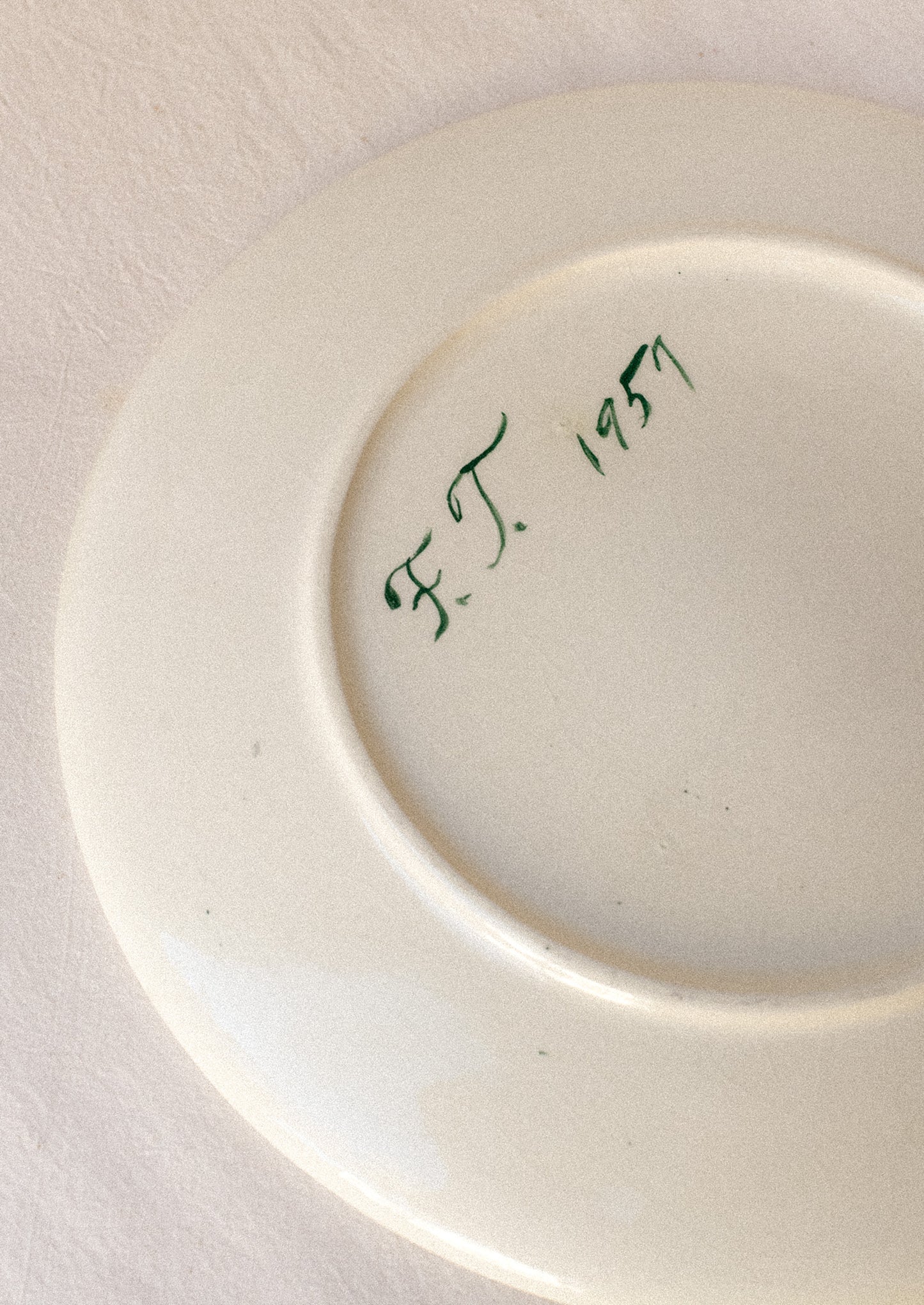 A signature on the back of a ceramic plate.