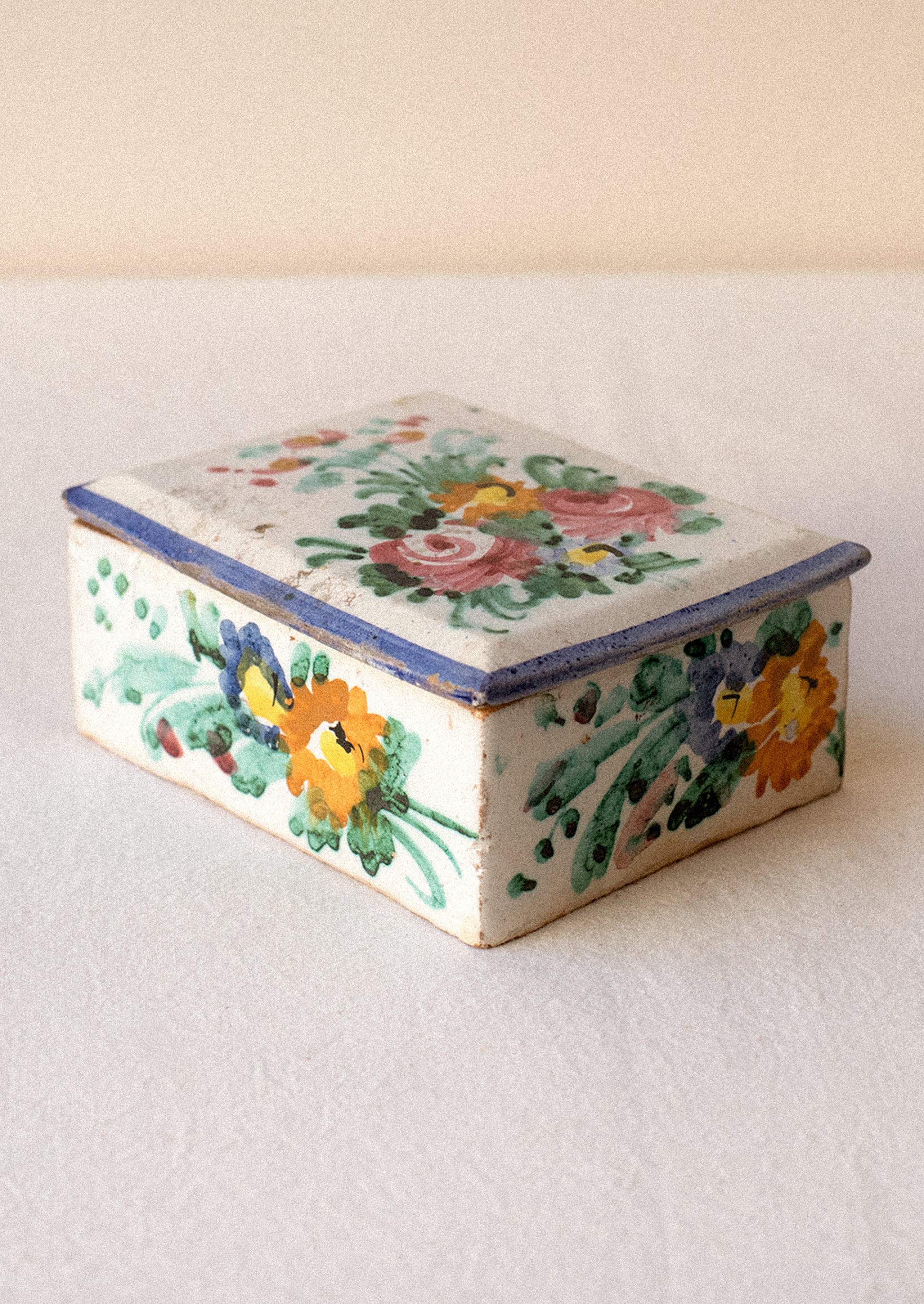 Decorative ceramic box with floral patterns on a plain background