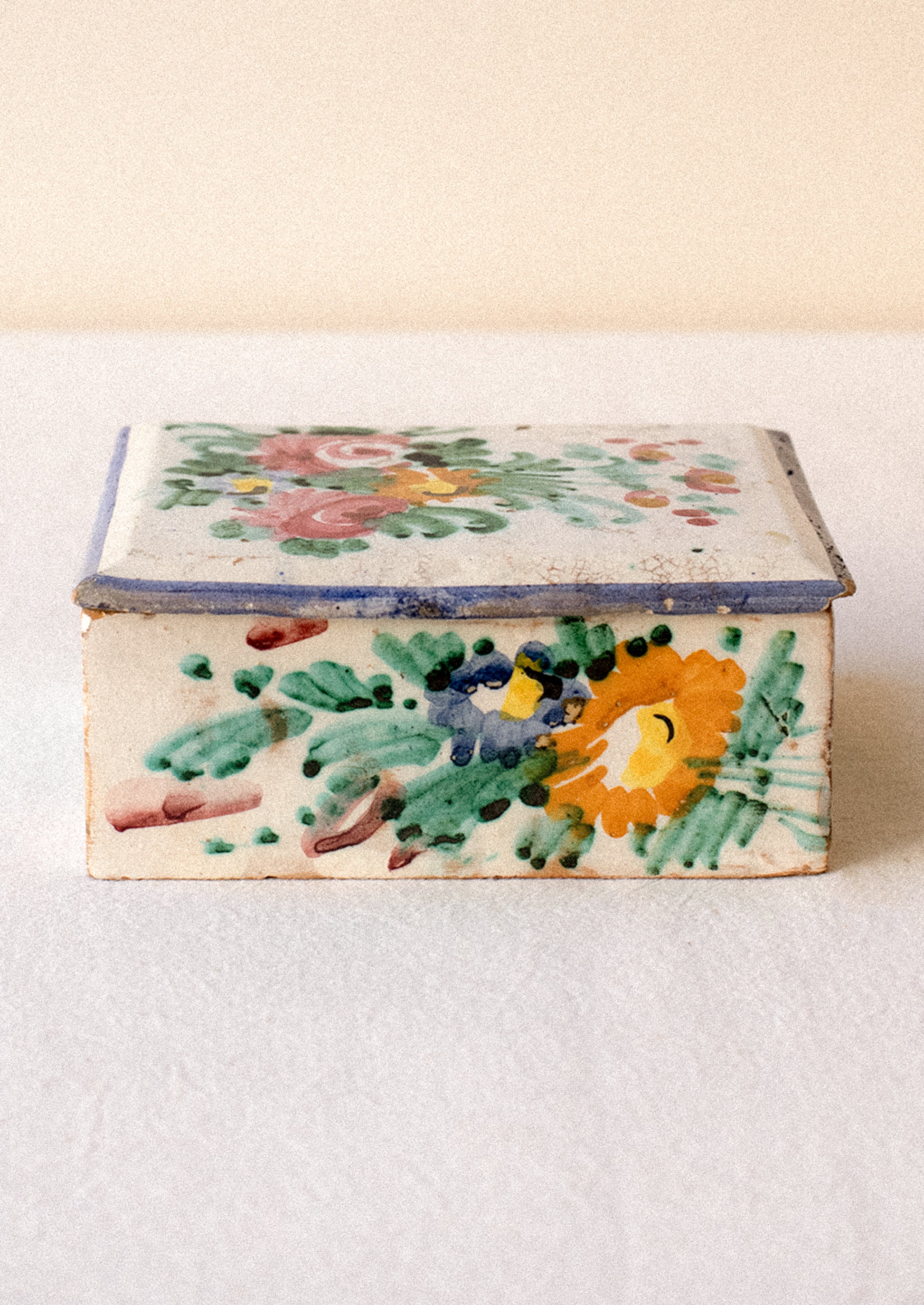 Decorative ceramic box with floral patterns on a plain background