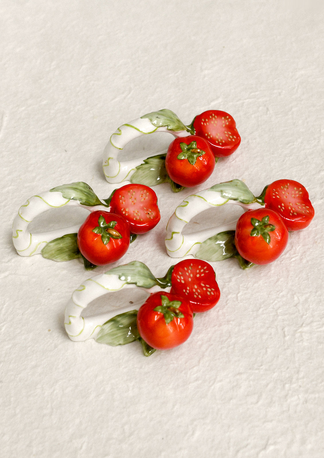A set of 4 napkin rings with tomato motif.
