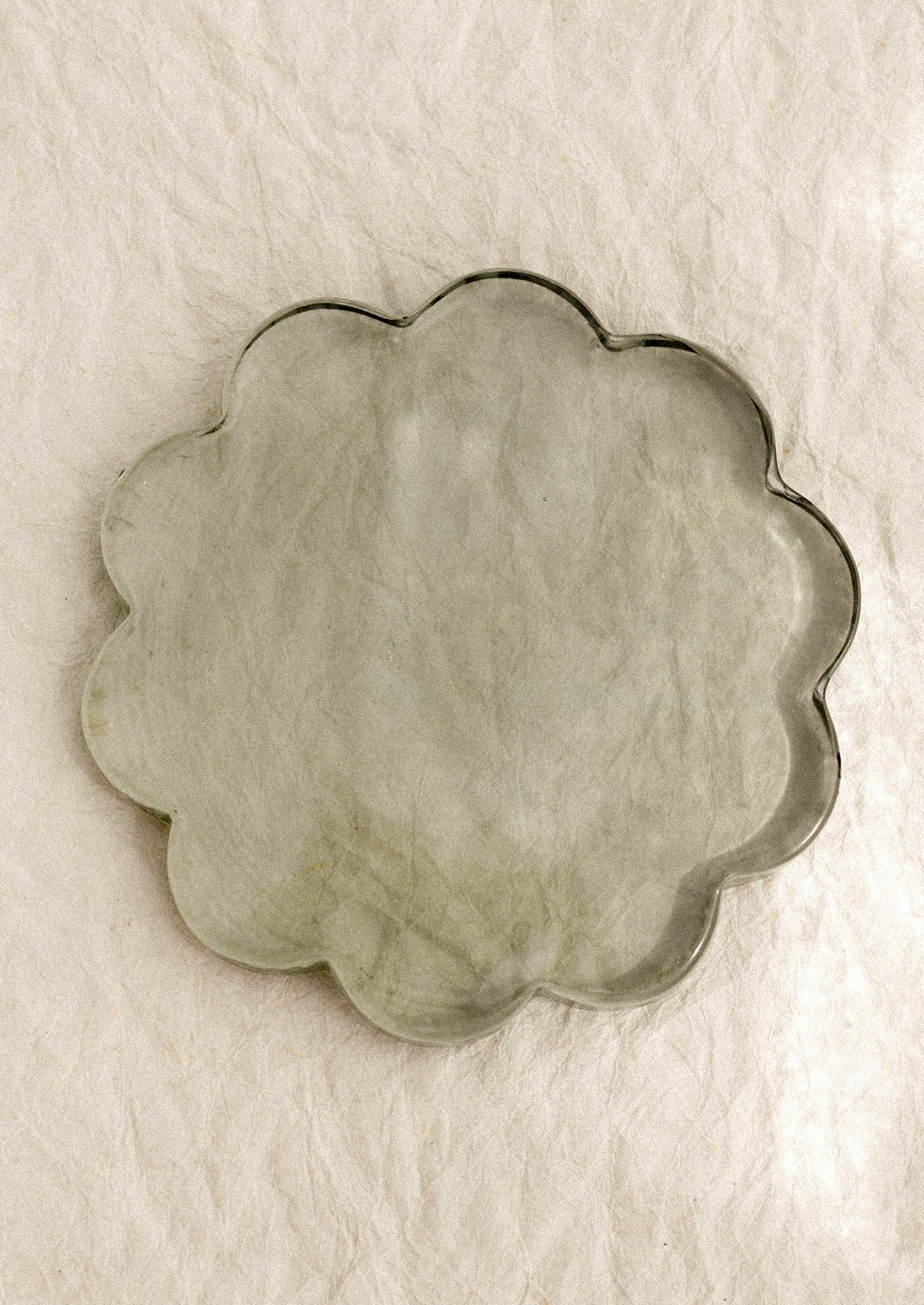A floral-shaped glass coaster in clear green tint.