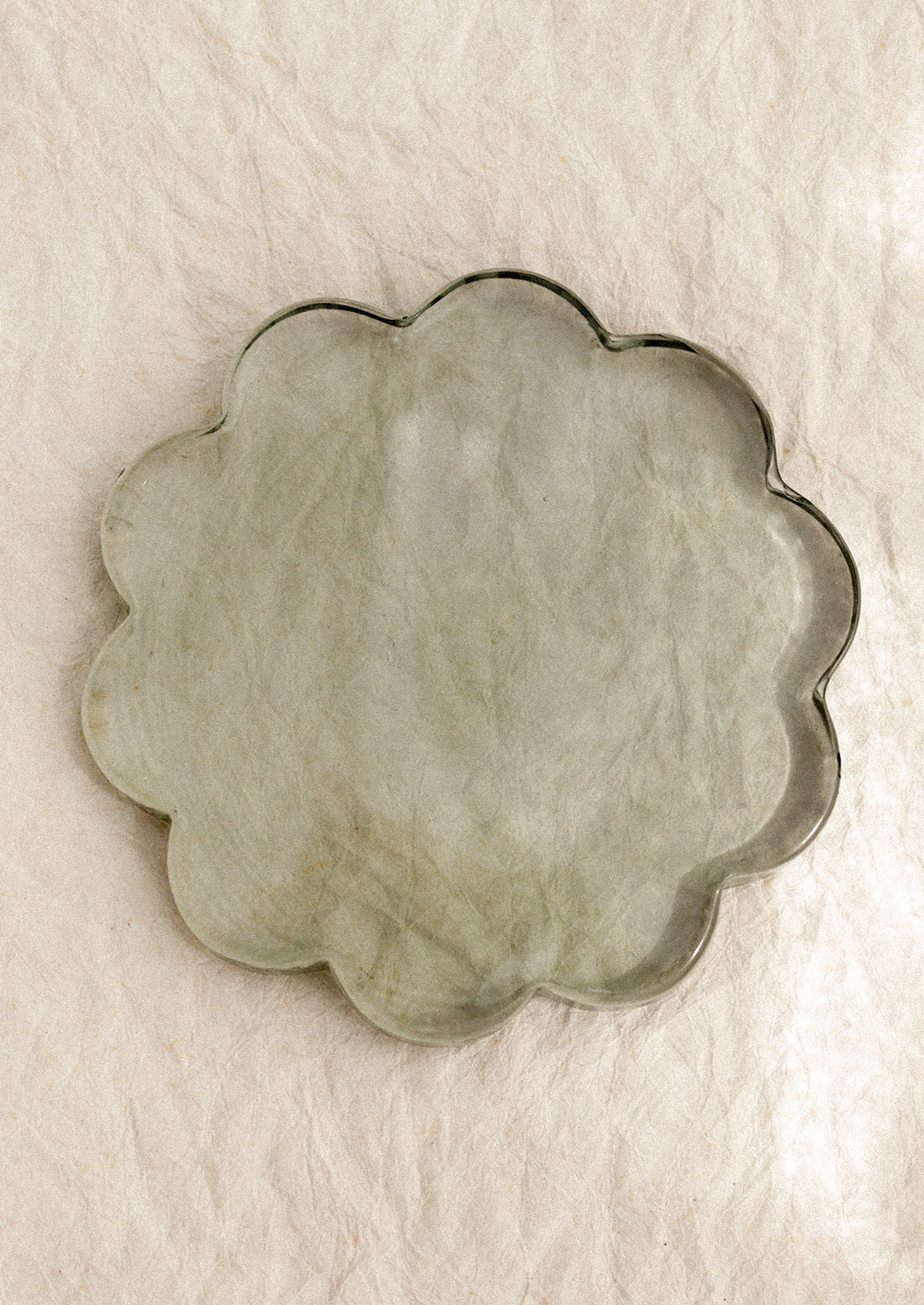 A floral-shaped glass coaster in clear green tint.