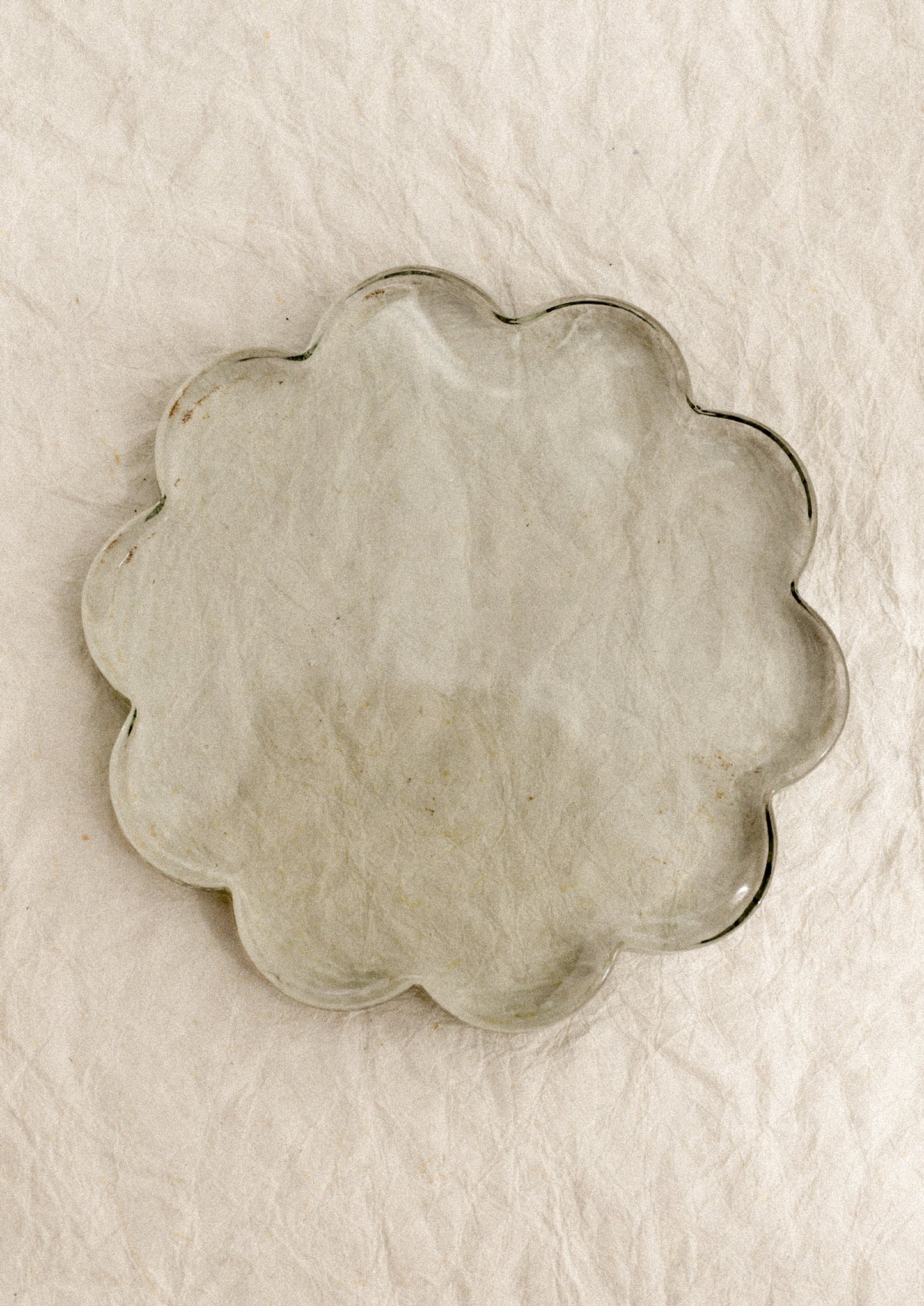 A floral-shaped glass coaster in clear tint.