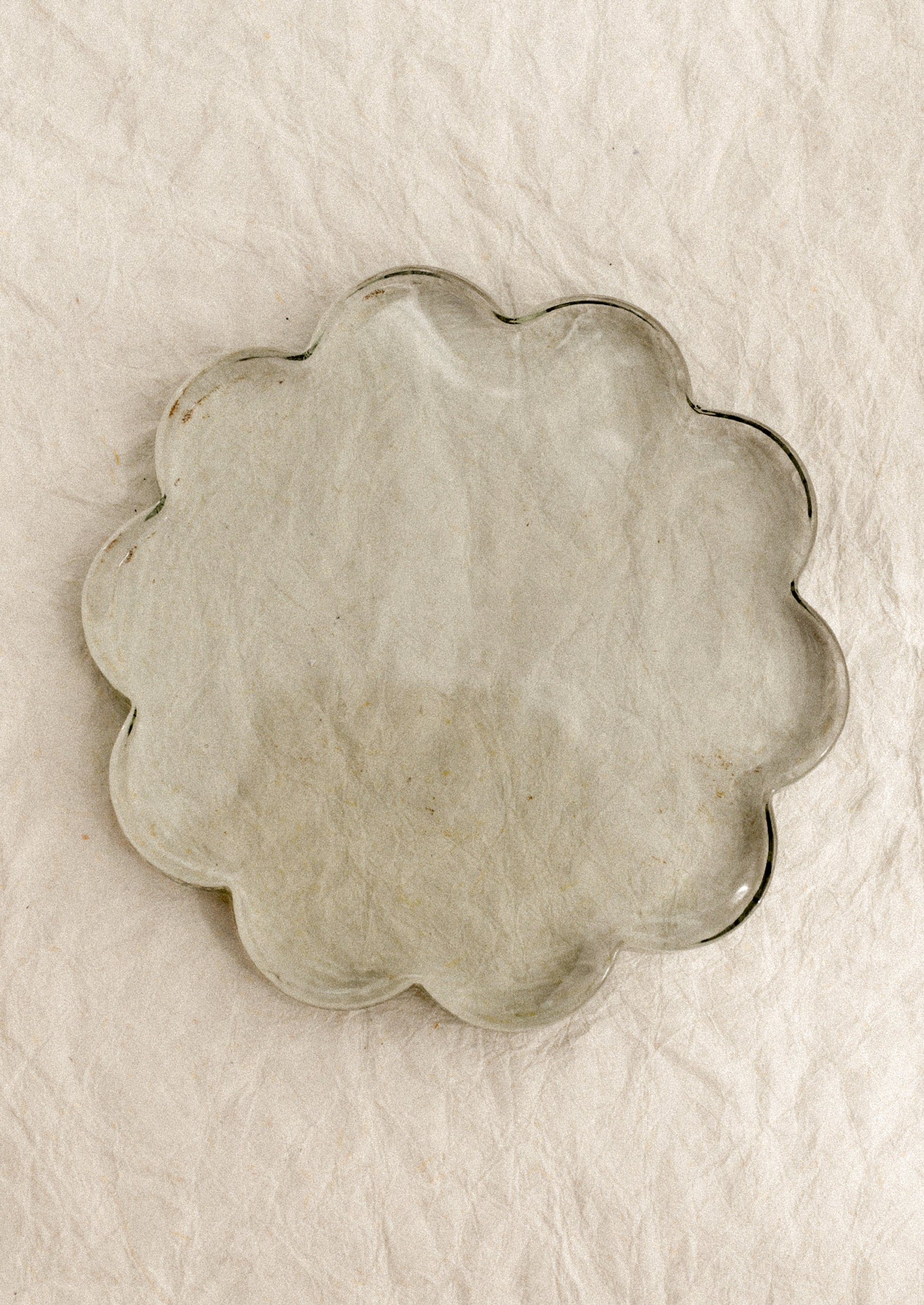A floral-shaped glass coaster in clear tint.