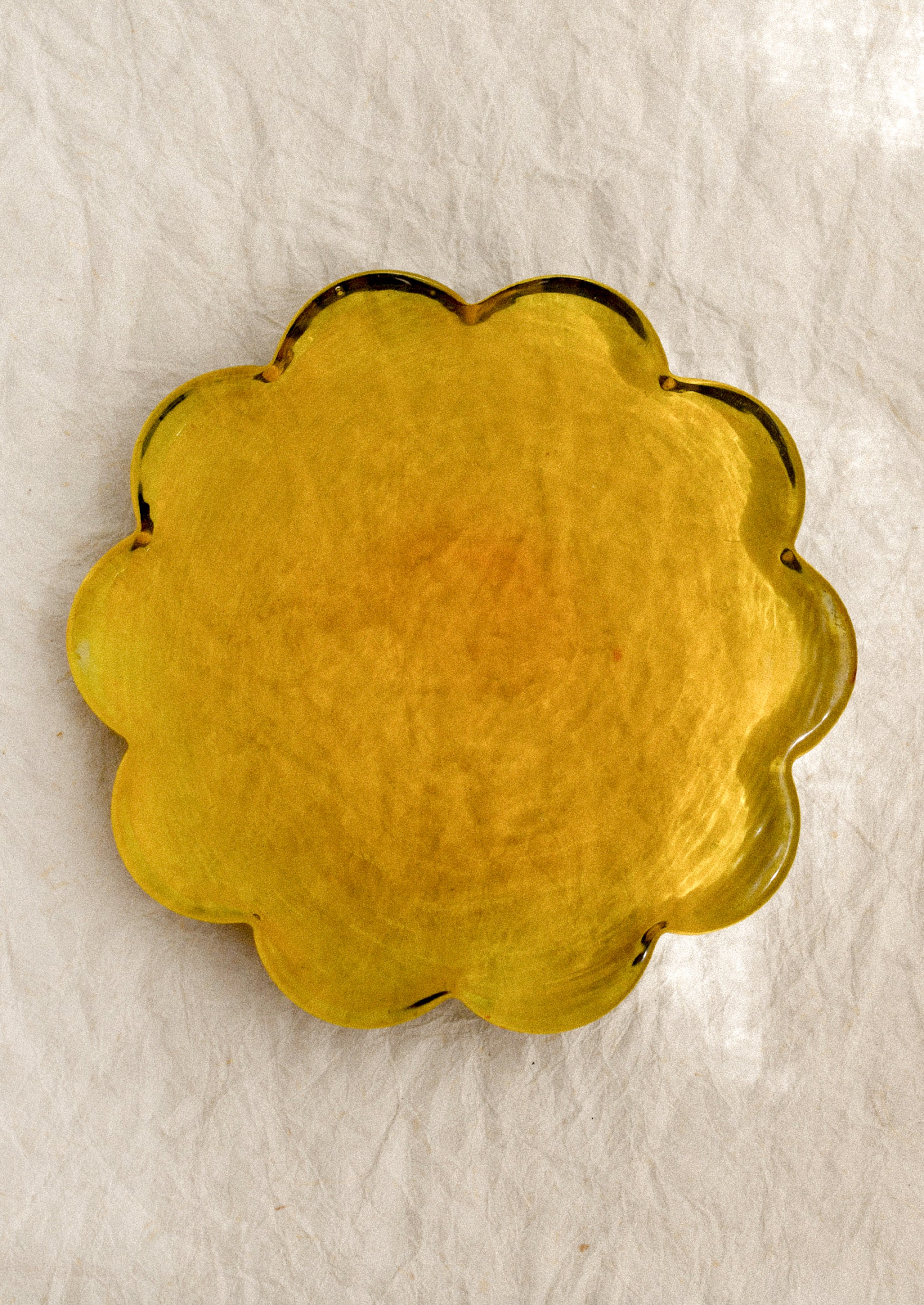 A floral-shaped glass coaster in amber tint.