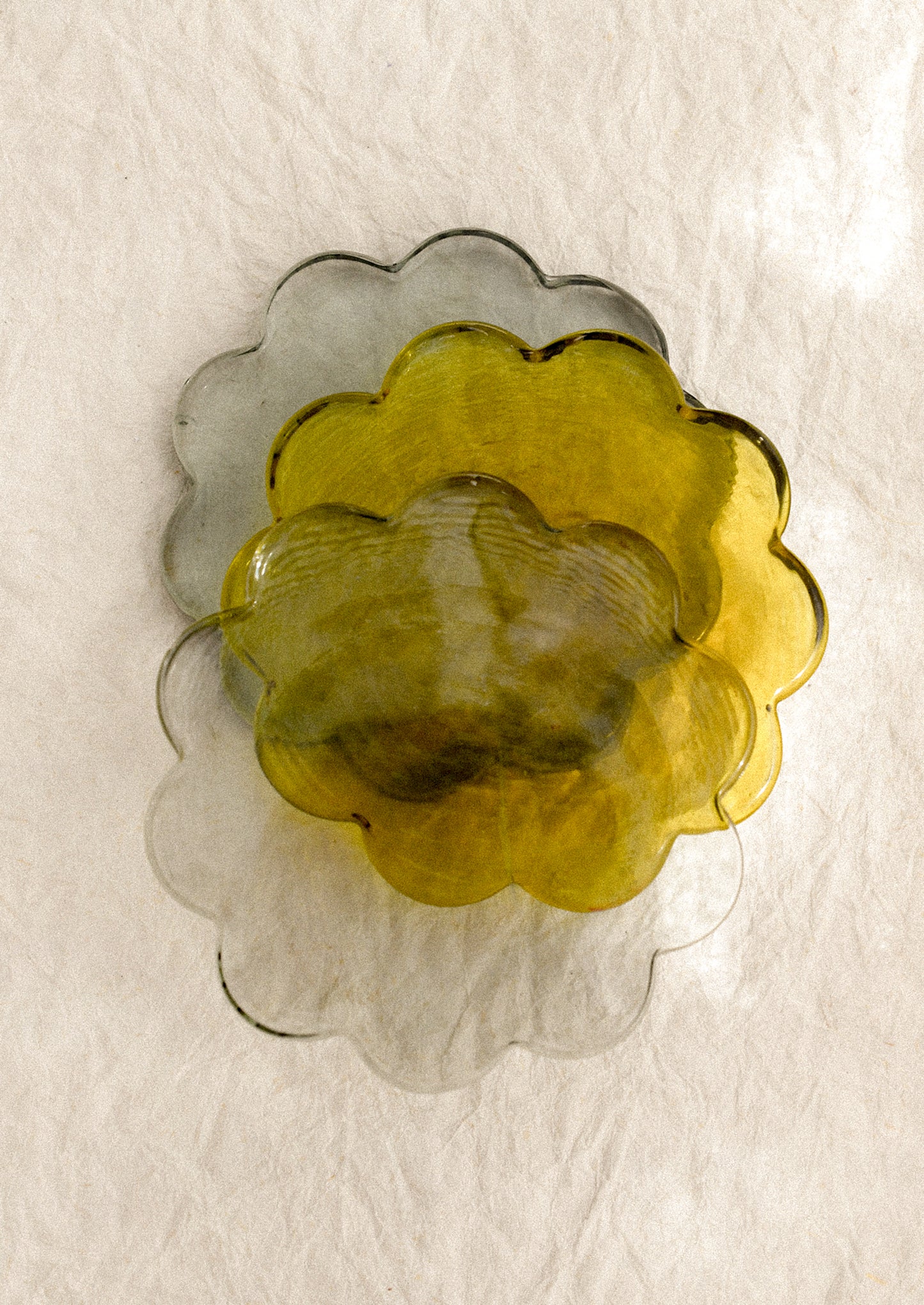 Three floral-shaped glass coasters in yellow, gray, and green.