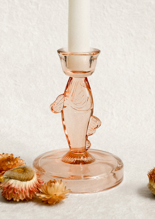 Pink glass fish-shaped candle holder with a white candle.