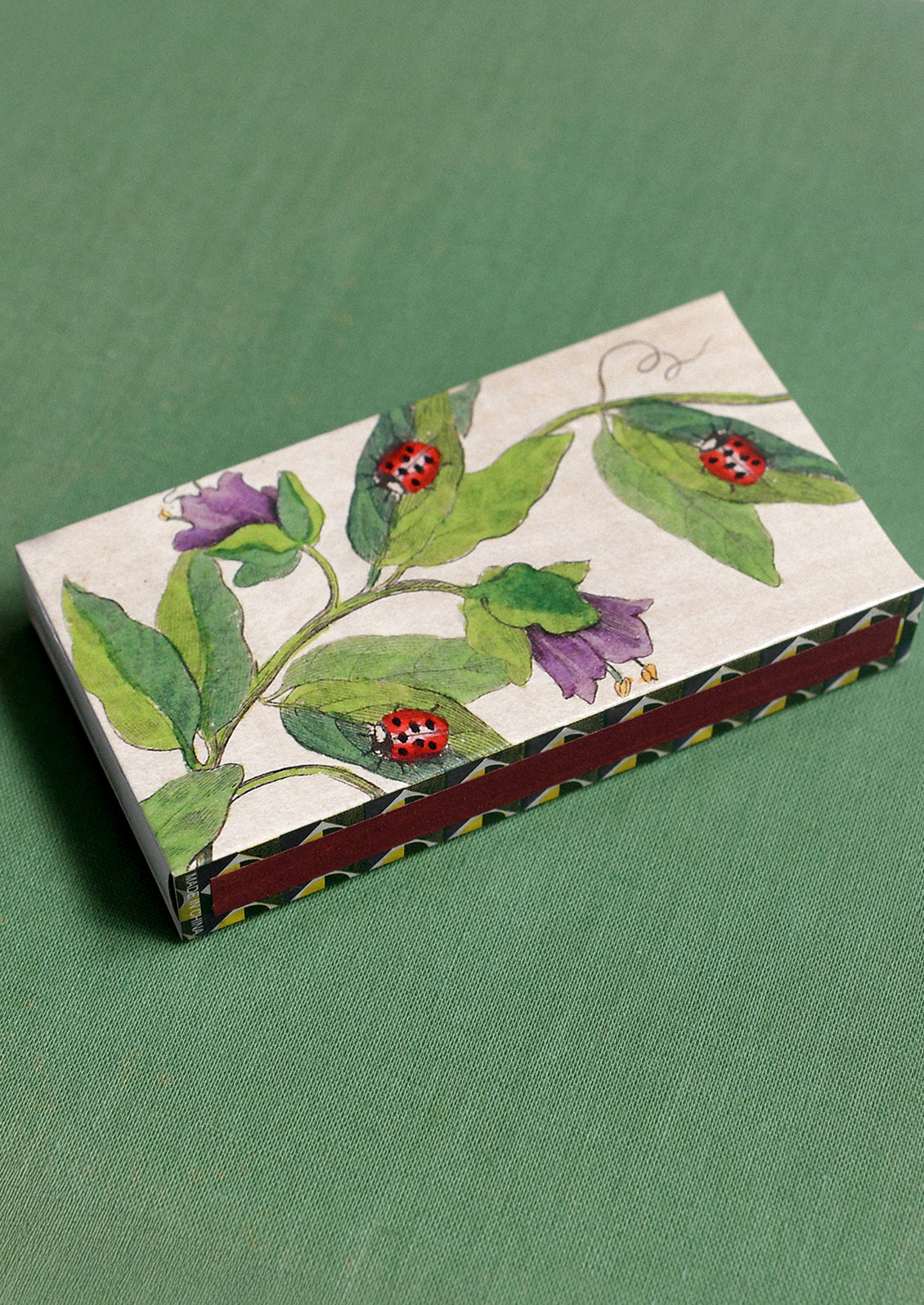 A matchbox with garden ladybug design.