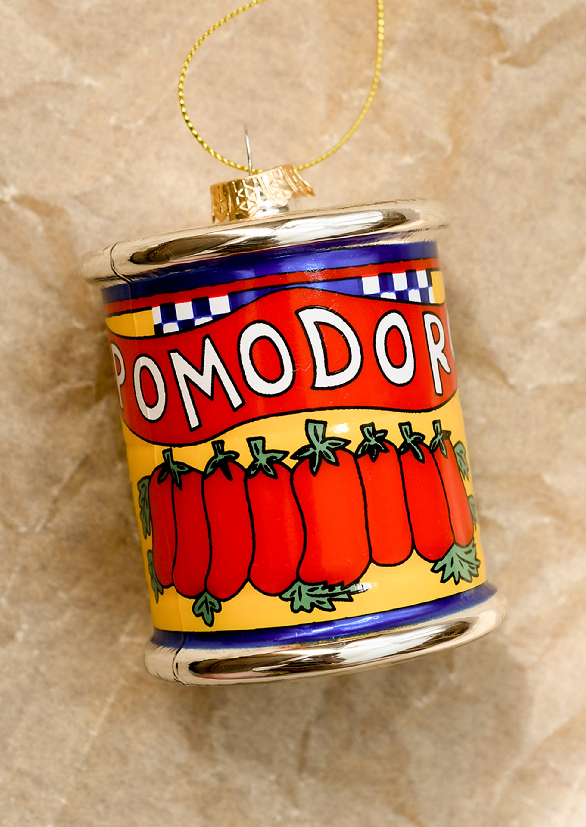 Decorative can ornament with tomato design on a textured beige background.