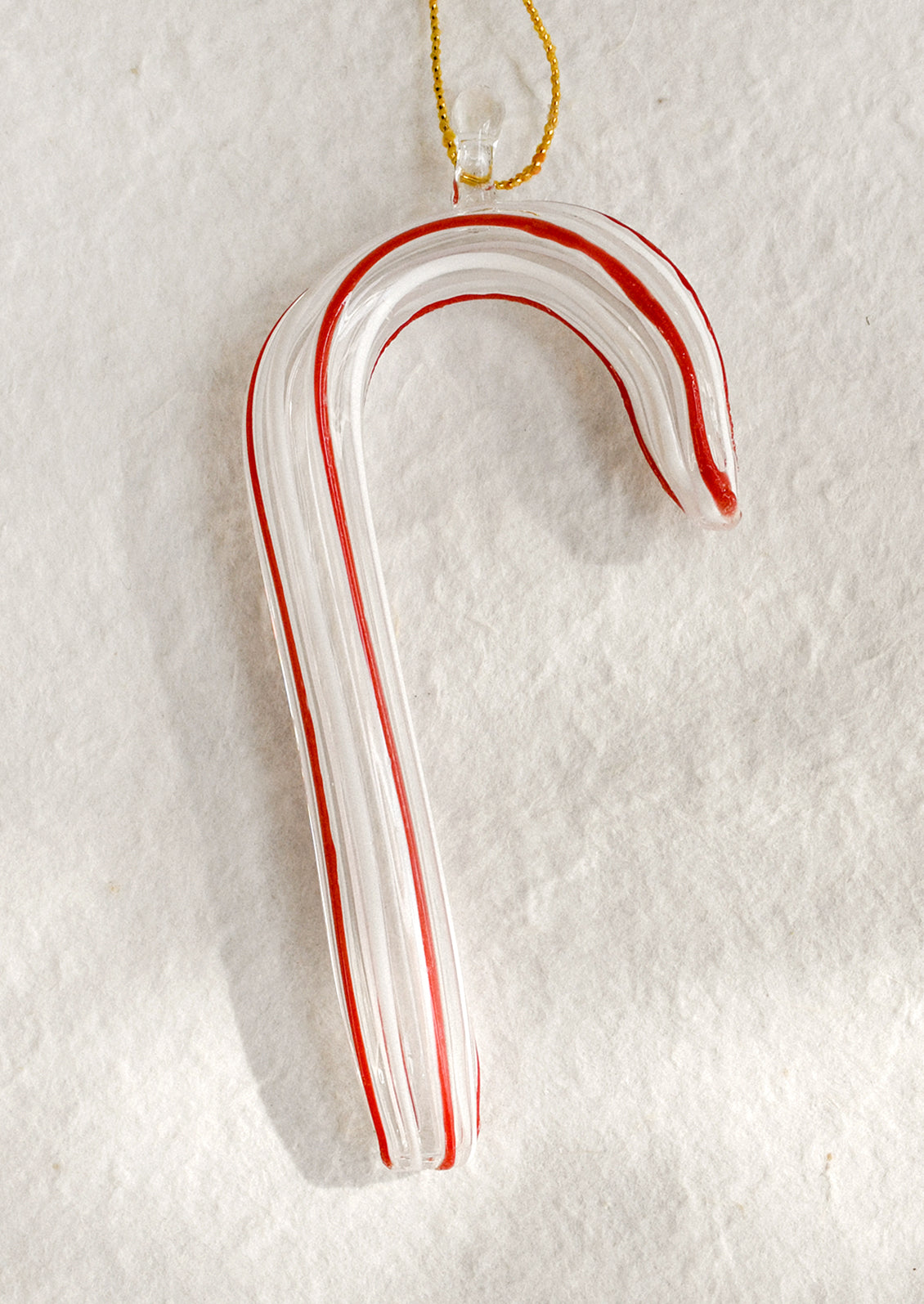 Glass candy cane ornament with red and white stripes on a white background