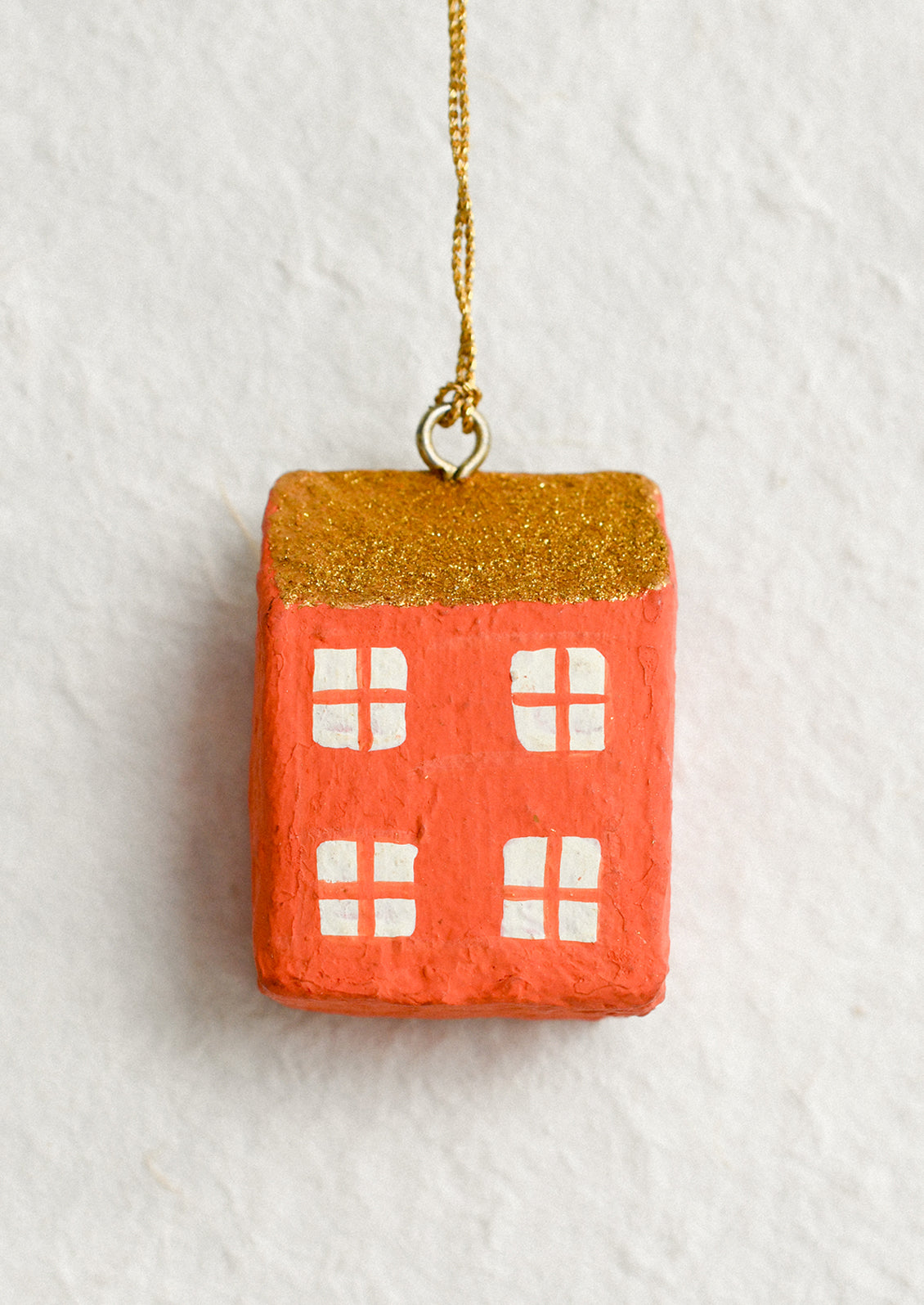 Decorative house ornament with gold roof and red body.