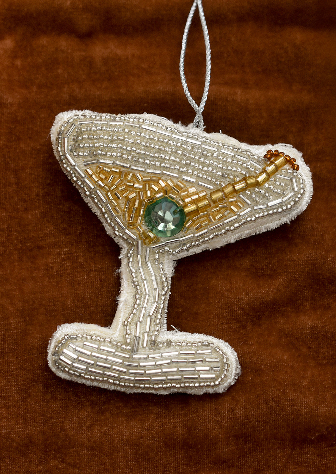 Beaded martini glass ornament on a brown background