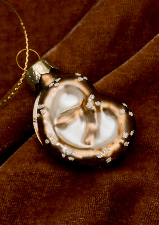 A small glass ornament in the shape of a soft pretzel.