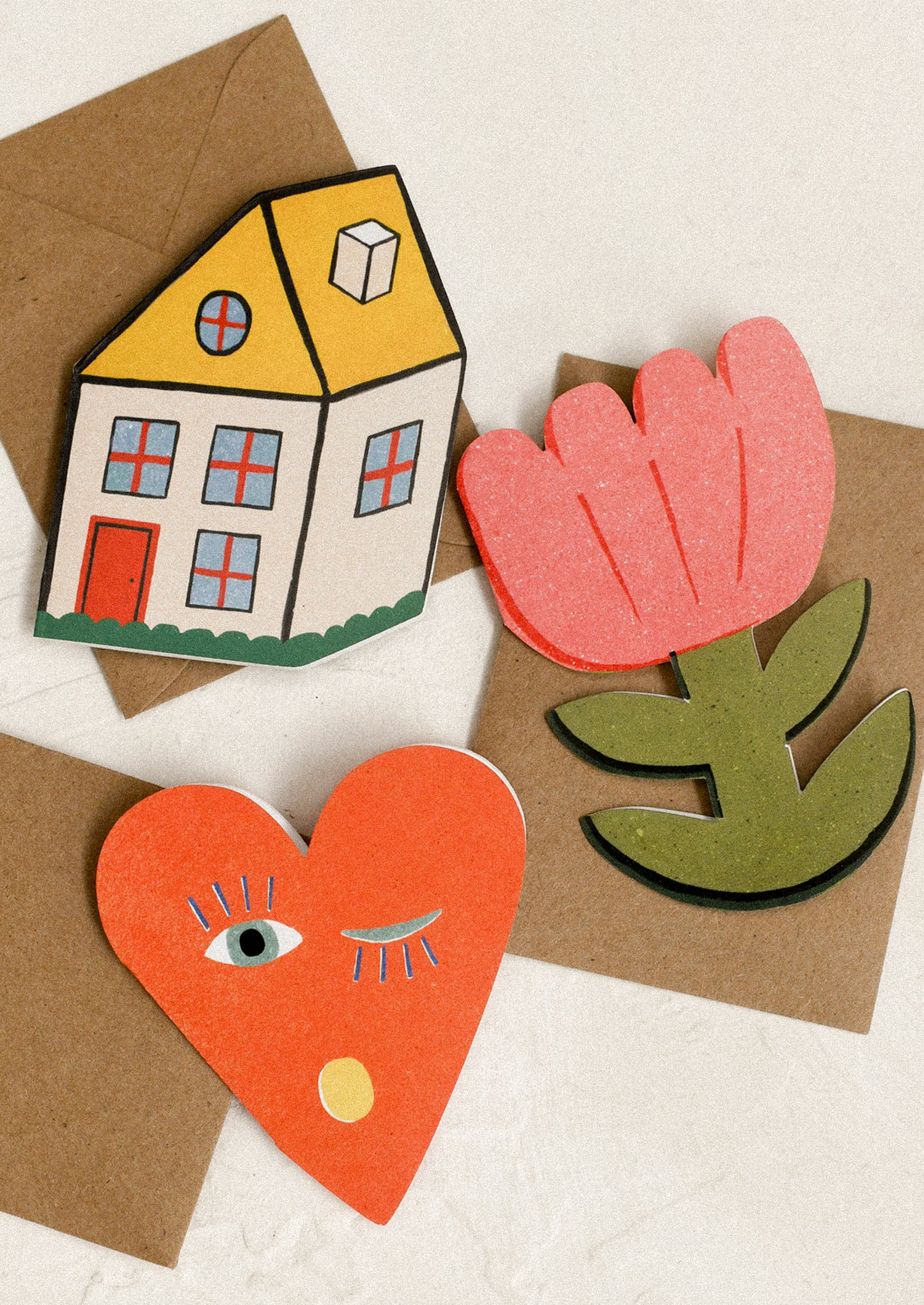 Colorful paper cards of a house, heart, and flower.