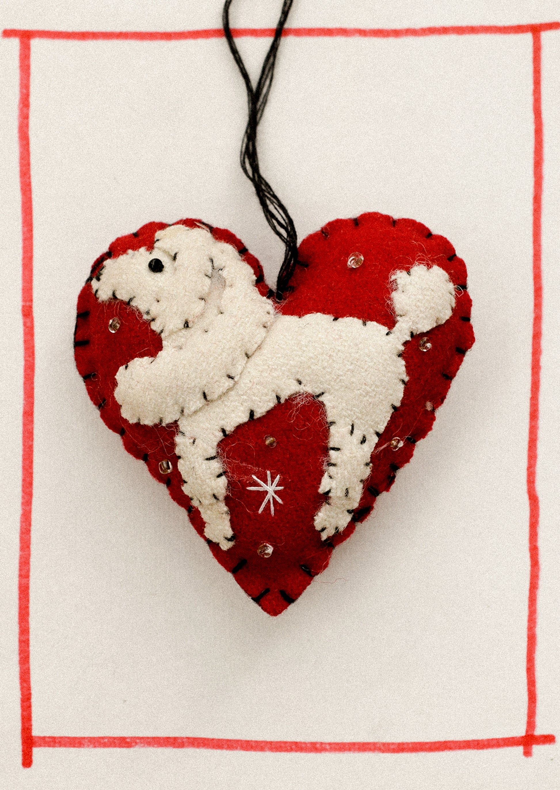 Heart-shaped ornament with a white dog design on a red background