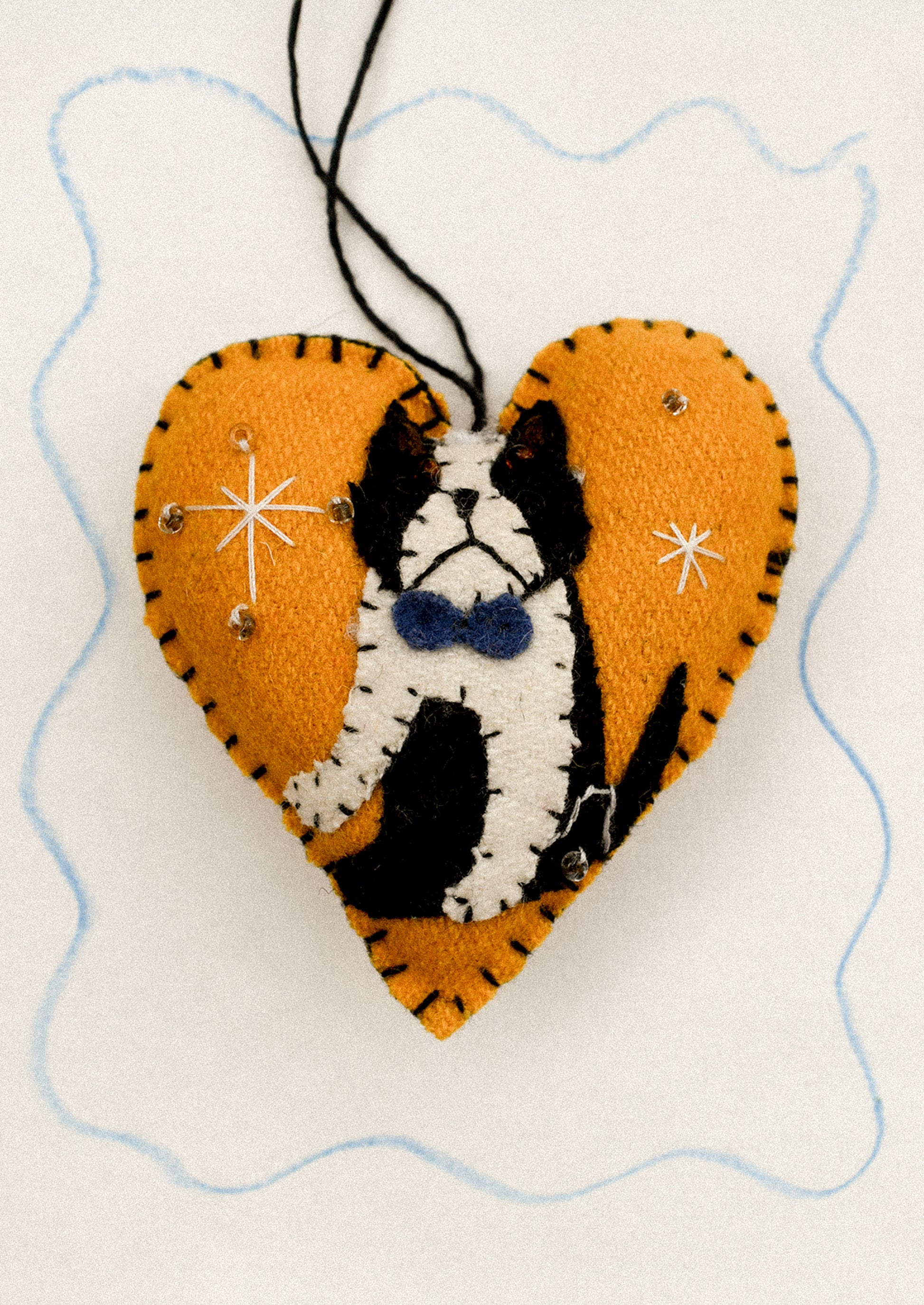 Heart-shaped ornament with a black and white dog design on an orange background