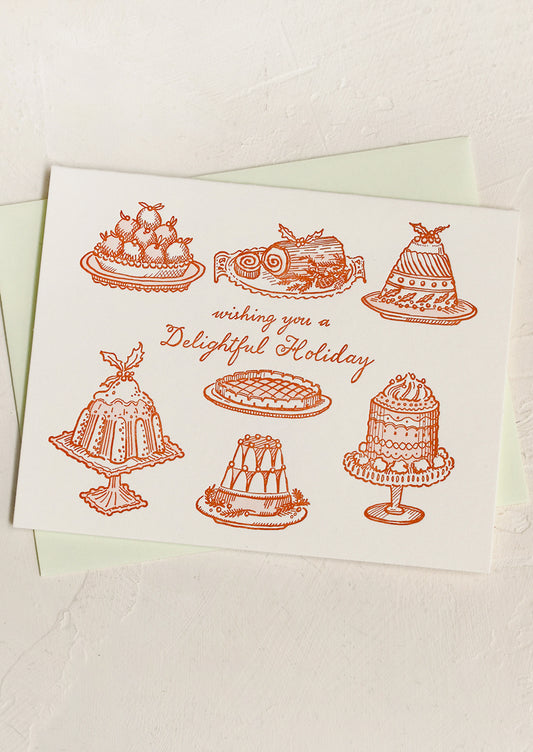 A letterpress printed card with imagery of fruitcakes, text reads "Wishing you a delightful holiday".