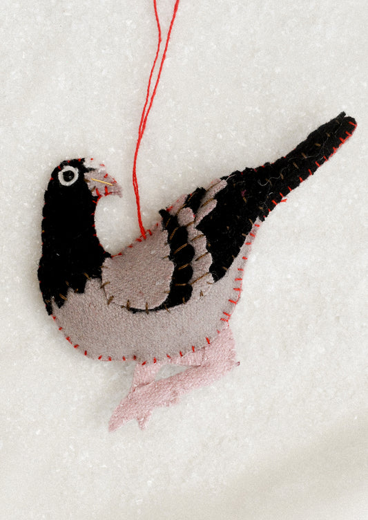 A felted ornament of a black pigeon.