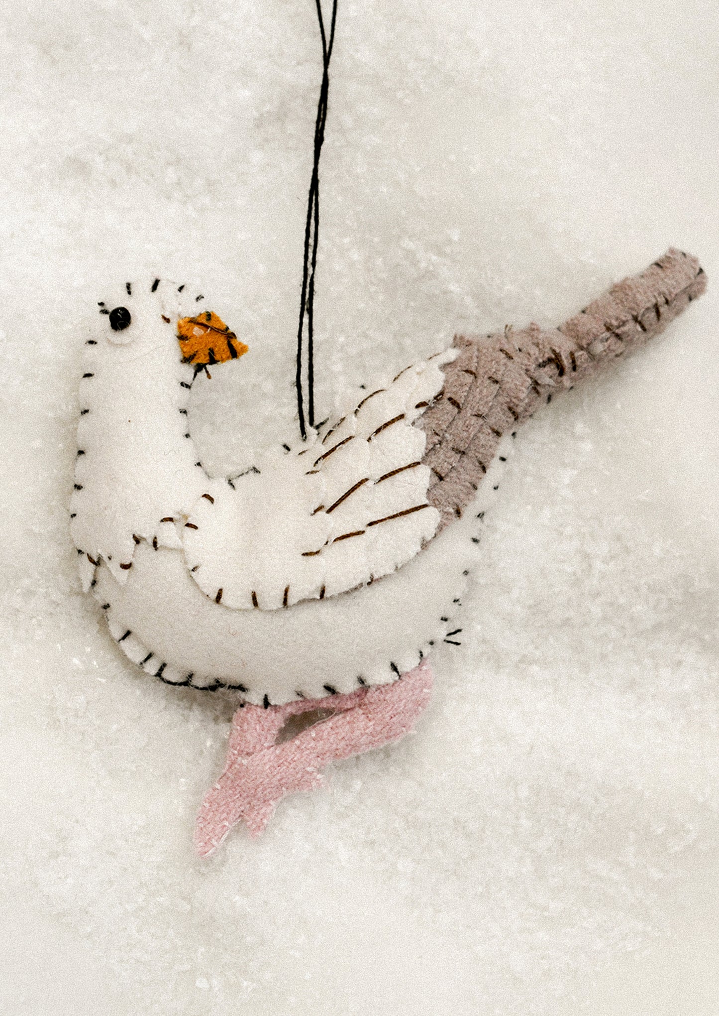 A felted ornament of a white pigeon.
