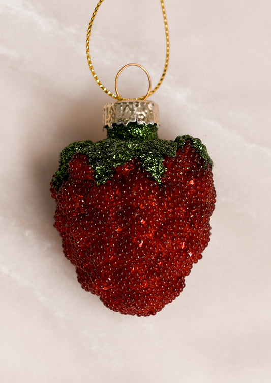 Decorative raspberry ornament with red beads and green top .