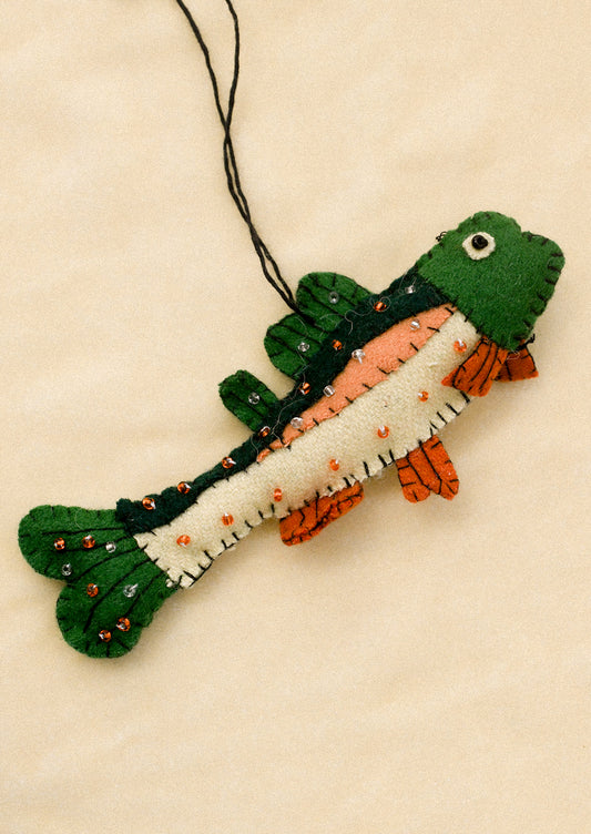 Felt fish ornament with green, orange, and white colors on a beige background