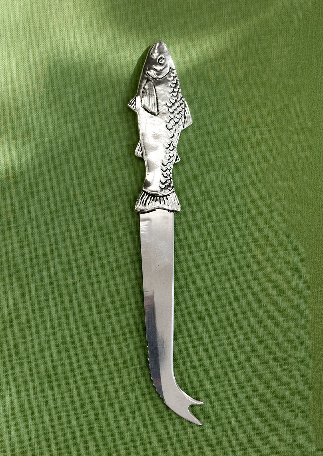 A pewter serrated cheese knife with pronged end, and fish-shaped handle.