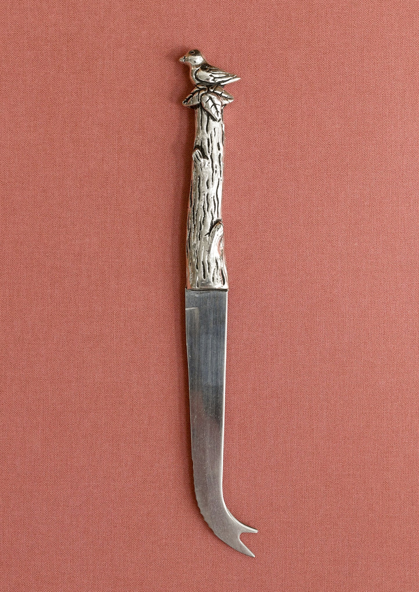 Decorative knife with a bird and branch handle on a pink background