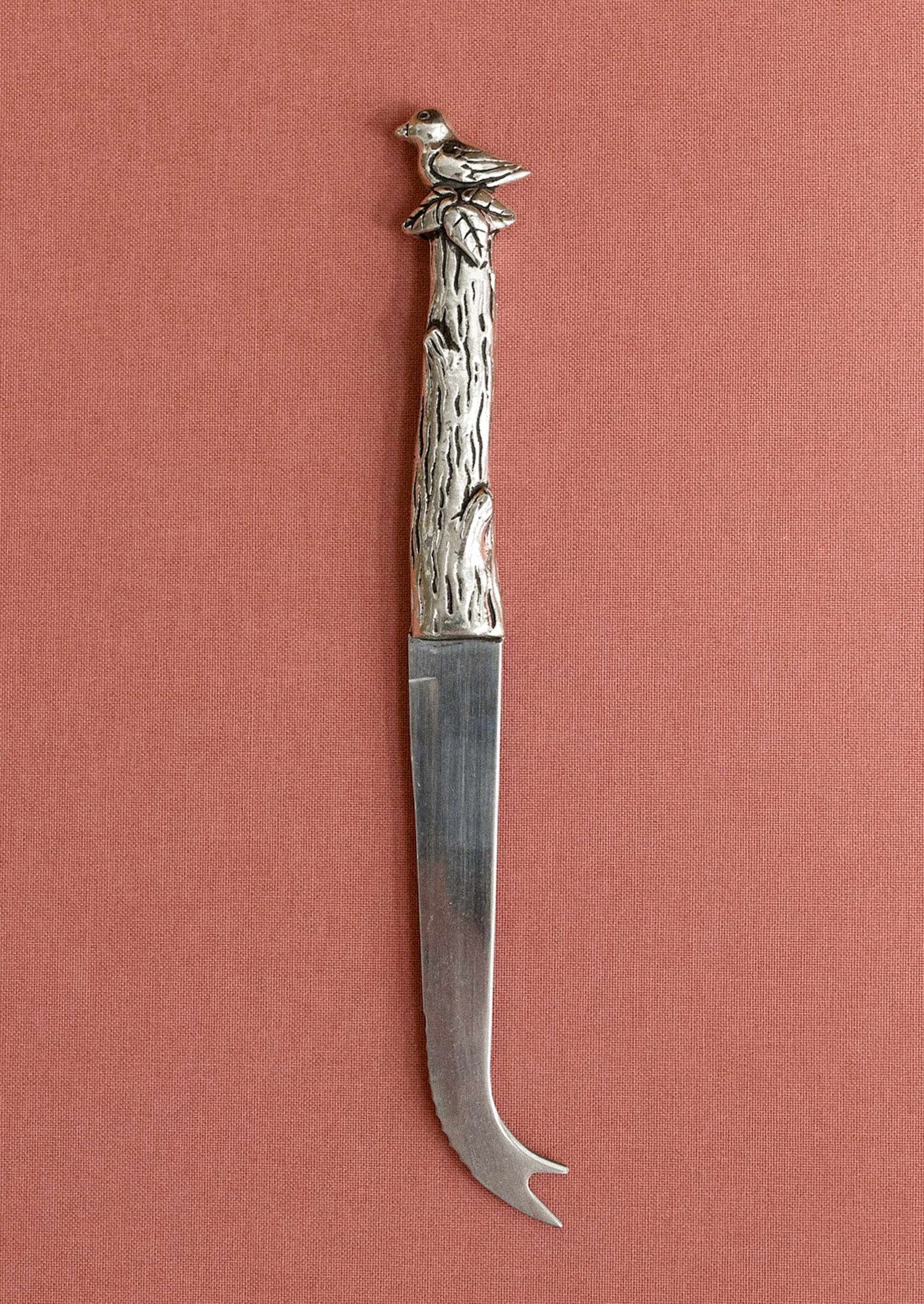 Decorative knife with a bird and branch handle on a pink background