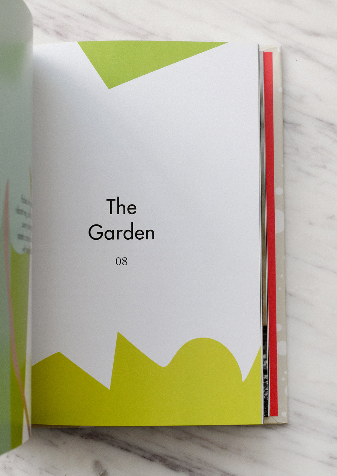 Book open to a page titled 'The Garden' with green and white design on a marble surface.