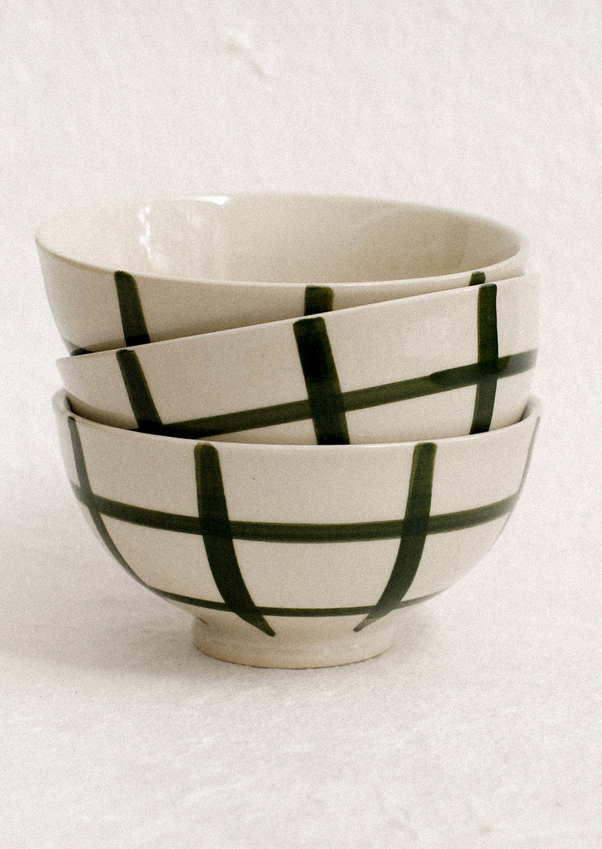 A stack of small white porcelain bowls with painted grid pattern.